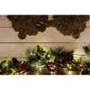 A close-up of a Christmas garland with lights, pine cones, and red berries. Produktbild-Vorschau
