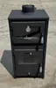 A black wood-burning stove with a chimney pipe on top, placed outdoors on a concrete surface. Produktbild-Vorschau