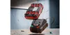 A battery charger and battery are shown floating in the air, with screws scattered on the surface below. Produktbild-Vorschau