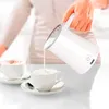 A person is pouring frothed milk from a milk frother into a cup of coffee. Produktbild-Vorschau
