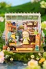 A miniature greenhouse scene with a doll, plants, and gardening tools. Anteprima dell’immagine prodotto