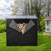 A black firewood storage cover with a transparent roof is shown outdoors in a grassy yard, with a small building and trees in the background. The front zipper is partially open, revealing a pile of firewood inside. Náhľad obrázku produktu