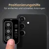 A hand is shown holding a camera lens protector template next to a smartphone's camera module. Produktbild-Vorschau