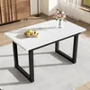 A white rectangular dining table with black metal legs, set on a light gray rug in a well-lit room. A bowl of apples and a vase of flowers are on the table. Produktbild-Vorschau