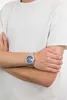 A man wearing a white t-shirt and a silver watch with a blue face. Produktbild-Vorschau