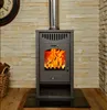 A wood-burning stove with a fire burning inside, set against a stone wall. Anteprima dell’immagine prodotto