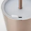 A close-up view of the top of a rose gold colored lamp, showing a USB-C port and a small white button. Podgląd zdjęcia produktu