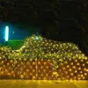 A net of warm white fairy lights is draped over bushes and a wooden fence at night. Produktbild-Vorschau