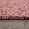 A close-up view of a pink shaggy rug on a wooden floor. Produktbild-Vorschau
