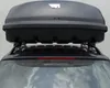 A black roof box mounted on the roof of a car. Produktbild-Vorschau