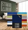 A stack of folded fitted sheets in various colors, with a bedroom scene in the background. Produktbild-Vorschau