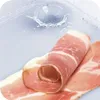 A close-up of rolled ham slices next to a water splash in a transparent container. Anteprima dell’immagine prodotto