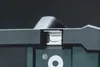 A close-up shot of the top part of a black electronic device, showing a metal latch mechanism and a registered trademark symbol. Podgląd zdjęcia produktu