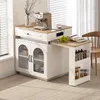 A multifunctional kitchen island with a pull-out table, coffee machine, and storage cabinets, set in a well-lit room with blinds and a chair. Podgląd zdjęcia produktu