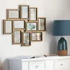 A multi-photo frame arrangement on a wall above a white dresser with a lamp and books. Podgląd zdjęcia produktu