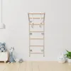 A wooden climbing frame with gymnastic rings is mounted on a white brick wall in a child's room. A teddy bear and a giraffe toy are on a white cabinet to the left, and a white bunny-shaped ceramic decoration and a potted plant are on the right. Produktbild-Vorschau