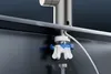 Close-up view of a faucet installation, showing a mounting bracket and water hose connection. Podgląd zdjęcia produktu