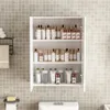A white bathroom cabinet filled with various cosmetic products, mounted on a tiled wall. Náhľad obrázku produktu