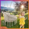 A child playing in a sunny meadow with a hanging chair in the background. Náhled obrázku produktu