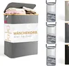 A grey fabric laundry basket with a wooden lid is shown, filled with clothes. The basket has a label with text and icons. Produktbild-Vorschau