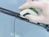 A hand is using a small green and white device to repair a car's windshield wiper blade. Produktbild-Vorschau