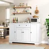 A white sideboard with drawers and doors, a microwave, and shelves with kitchen items in a bright room. Voir les images du produit