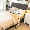 A laptop table on wheels is placed next to a bed in a bedroom. Produktbild-Vorschau