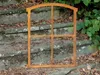 A rusty metal window frame is placed on outdoor stone steps, surrounded by fallen leaves and greenery. Produktbild-Vorschau