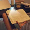 A person is reading a book with a small clip-on LED light illuminating the pages. Produktbild-Vorschau