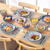 A table set with multiple plates of food and dishes, suggesting a meal setting. Produktbild-Vorschau
