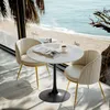 A marble-top bistro table with two chairs set up on a balcony overlooking a beach and the ocean. Produktbild-Vorschau