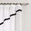 A close-up view of white sheer curtains with black ribbon trim, hanging from a curtain rod. Produktbild-Vorschau
