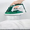 A hand is holding a green and white steam iron over a white shirt. Produktbild-Vorschau