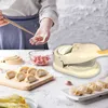 A person is making dumplings using a dumpling maker, with ingredients and finished dumplings visible. Produktbild-Vorschau