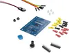 A collection of electronic components for a learning kit, including a circuit board, wires, buttons, and connectors, laid out on a white background. Produktbild-Vorschau