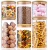 Sechs klare Glasvorratsgläser mit hellen Bambusdeckeln, gefüllt mit verschiedenen Trockenwaren wie Nüssen, Linsen, Marshmallows, Nudeln und Brotstangen Voir les images du produit