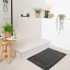 A bathroom scene with a rug, stool, plants, and shower. Anteprima dell’immagine prodotto