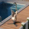 A hammock chair is set up next to a swimming pool on a wooden deck. Náhled obrázku produktu