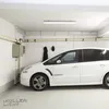 A white car parked in a garage with a light fixture on the ceiling. Produktbild-Vorschau