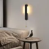 A modern black wall lamp with a pull chain is mounted on a light gray wall above a sofa and a small side table with a bird figurine. Anteprima dell’immagine prodotto