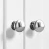 A close-up view of two silver cabinet knobs on white cabinet doors. Produktbild-Vorschau