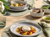 A beautifully set table with plates of food, cutlery, and glasses, suggesting a meal setting. Produktbild-Vorschau
