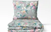 A folded duvet and pillow set with a floral and bird pattern on a light gray background. Produktbild-Vorschau
