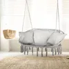 A hanging chair with pillows is shown in a room with blinds and a rug. Voir les images du produit
