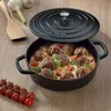 A cast iron pot filled with meatballs, tomatoes, and cheese, with a wooden spatula and cherry tomatoes on the side. Náhled obrázku produktu