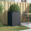 A dark gray planter with a green bush sits on grass next to a wooden fence and a metal chair and table. Anteprima dell’immagine prodotto