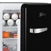 The inside of a black retro-style mini refrigerator is shown, with cans of drinks, an orange, and some packaged items visible. Produktbild-Vorschau