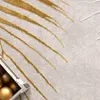 A close-up view of a rug with a leaf pattern and a box of ornaments. Anteprima dell’immagine prodotto
