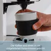 A hand holding a coffee cup under a coffee maker. Produktbild-Vorschau