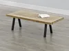 A wooden coffee table with black metal legs is shown on a wooden floor. Voir les images du produit